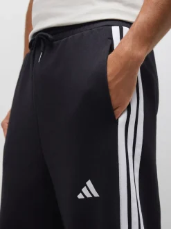 adidas Noir - Pantalons à jambe large en polaires à trois rayures Essentials